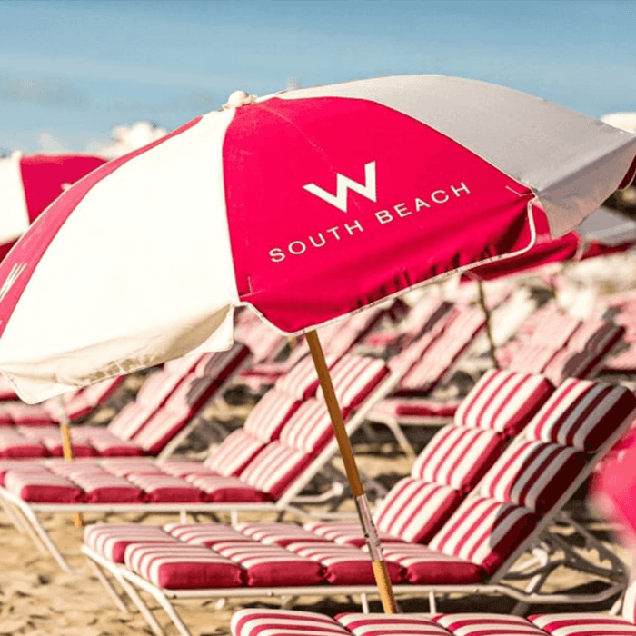 Red and white striped commercial umbrella with silk screen printed logo, demonstrating durable branding for beach resorts and outdoor lounge seating.